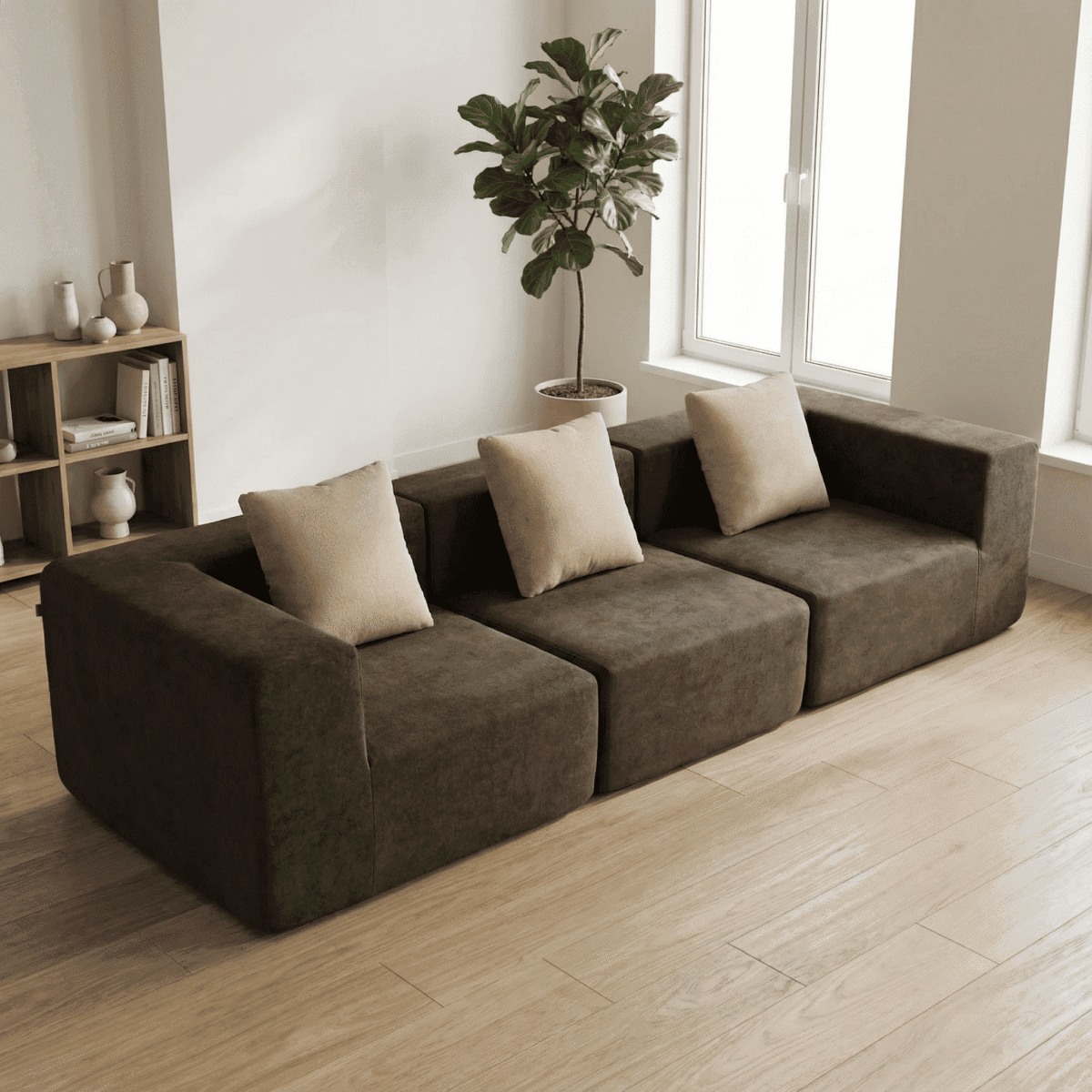 Salon minimaliste lumineux avec canapé marron contemporain, coussins beiges, plante verte et étagère en bois