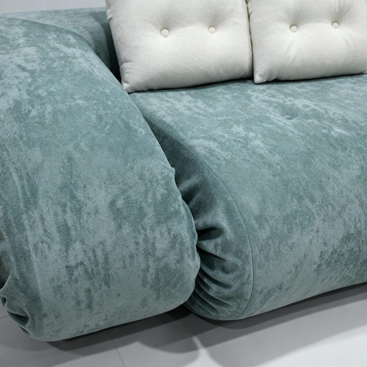 Canapé moderne bleu vert aux accoudoirs arrondis avec coussins blancs, design contemporain et confortable