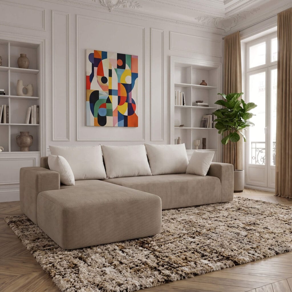 Un salon lumineux avec canapé beige et chaise longue, tapis berbère, étagères blanches, tableau coloré abstrait et plante verte près de la fenêtre.