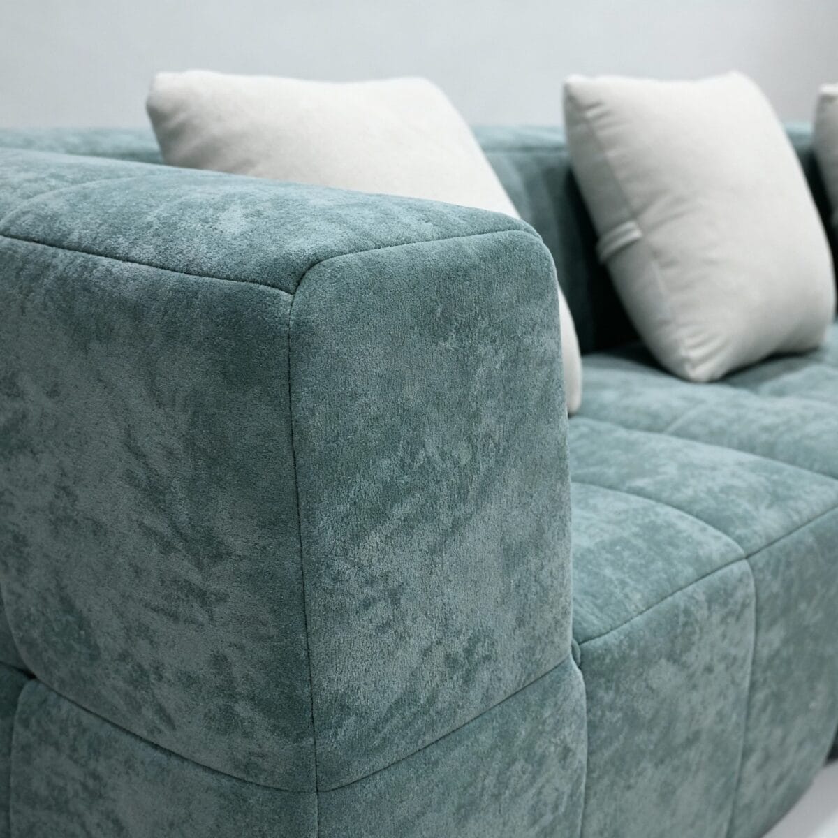 Canapé moderne vert d’eau texturé avec coussins crème, design contemporain pour salon élégant