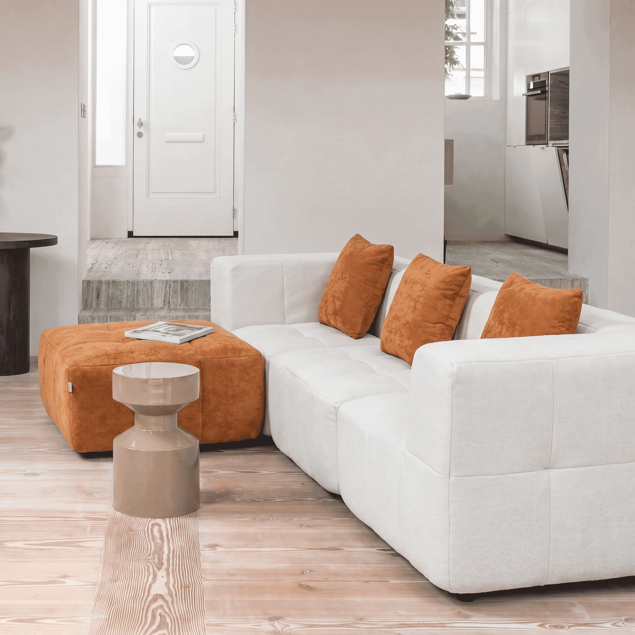 Sofa blanc avec coussins orange dans un intérieur lumineux.