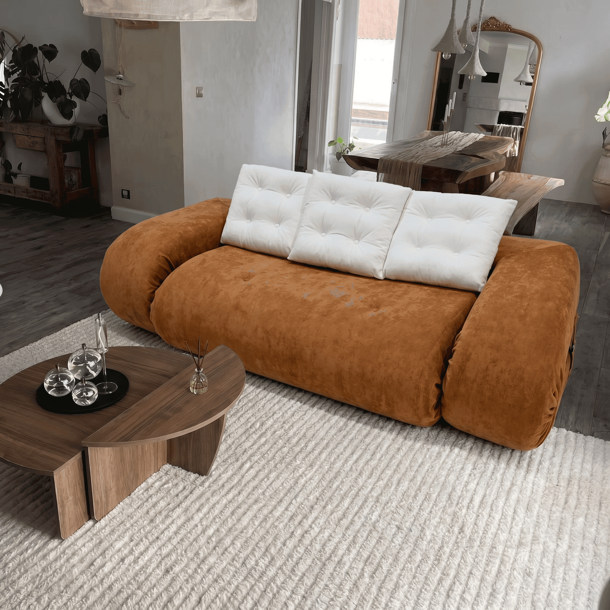 Canapé en velours marron avec coussins blancs, salon moderne et cosy.